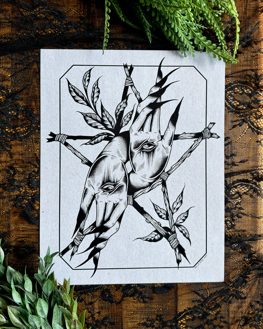a print with Witchy hands with an eye in the center of the palm and sticks forming a witchy star around it and leaves
