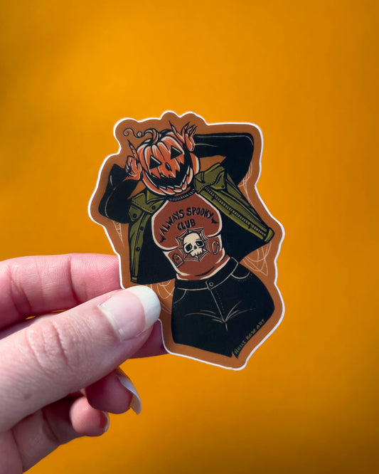 a pumpkin girl using her hands to make devil horns by her head wearing a shirt that says always spooky club shirt