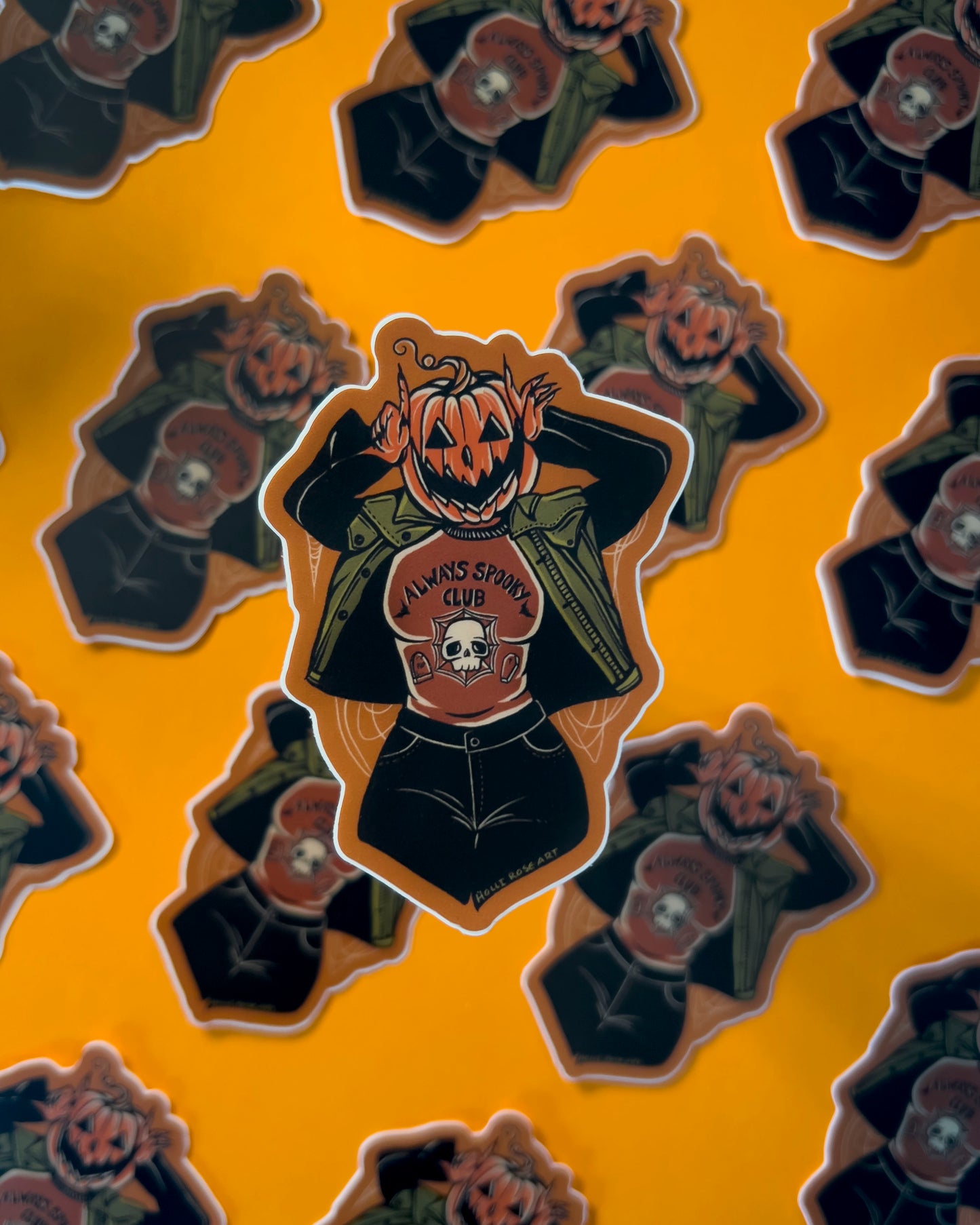 a pumpkin girl using her hands to make devil horns by her head wearing a shirt that says always spooky club shirt