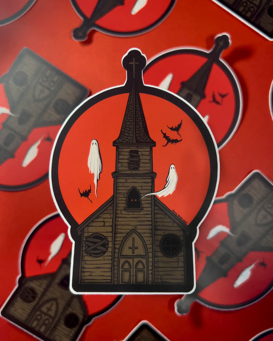 A sticker of a haunted church with ghosts and bats flying around and a red moon behind it
