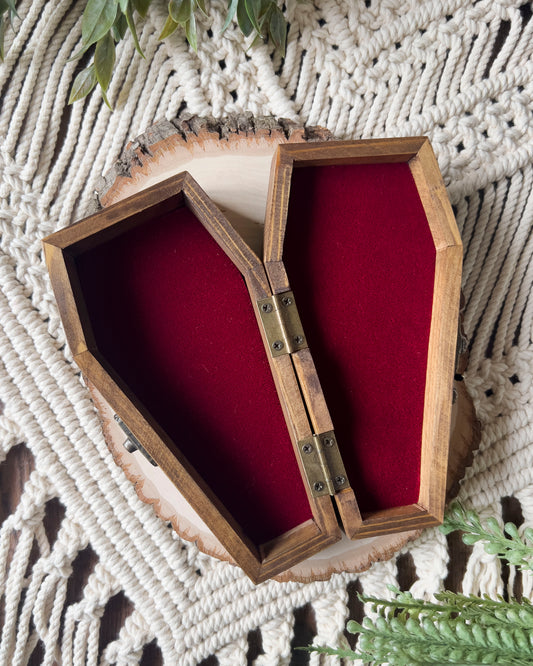 a coffin shaped trinket dish with red velvet on the inside