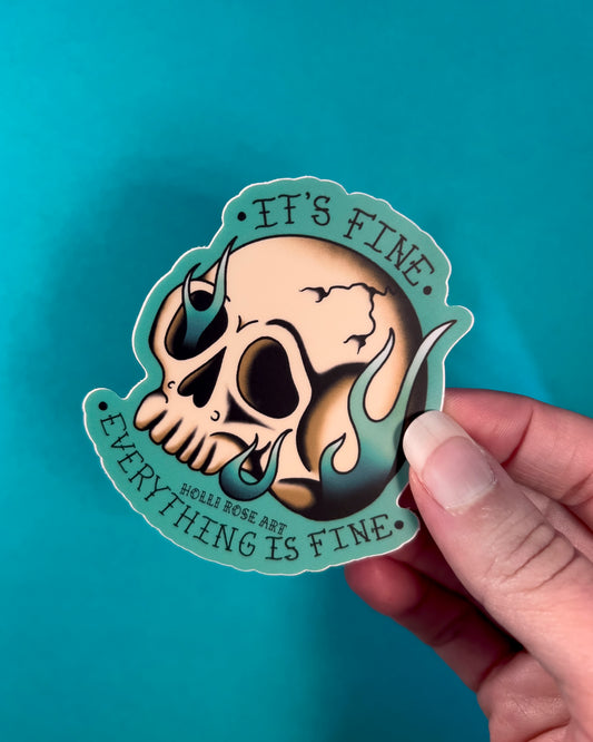 A sticker with a skull on fire saying "it's fine everything is fine"