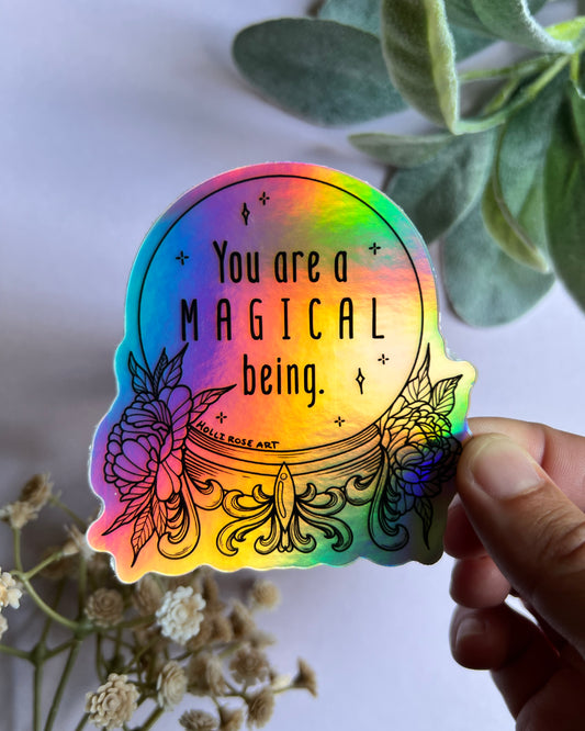 a colorful holographic sticker saying you are a magical being in a witch ball