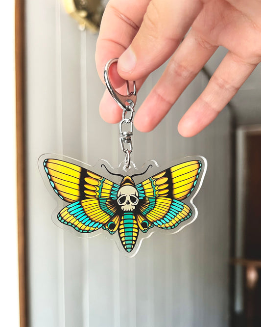 moth keychain with a skull in the center in teal and yellow