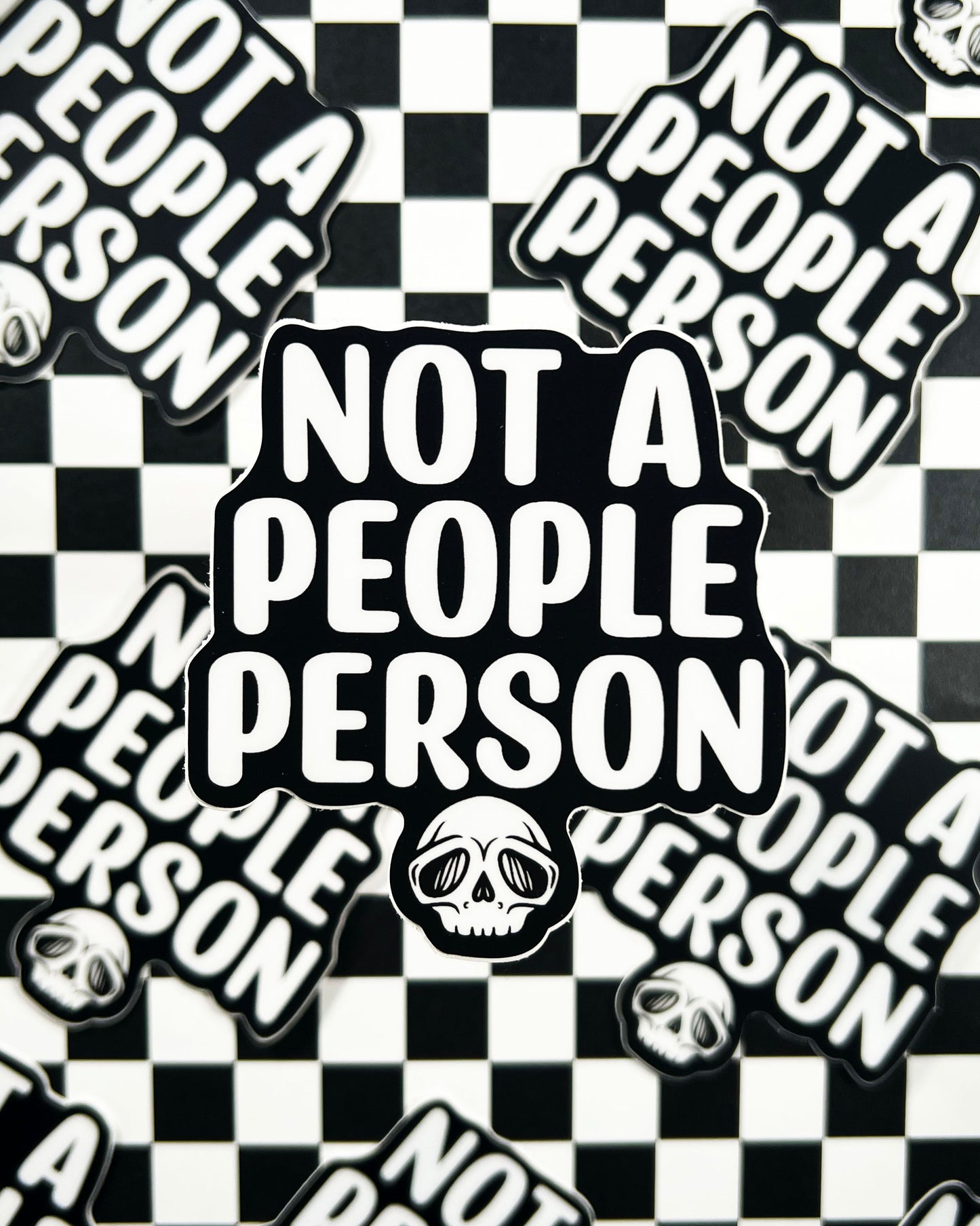 Stickers with 'Not a People Person' text and skull designs on a checkered background