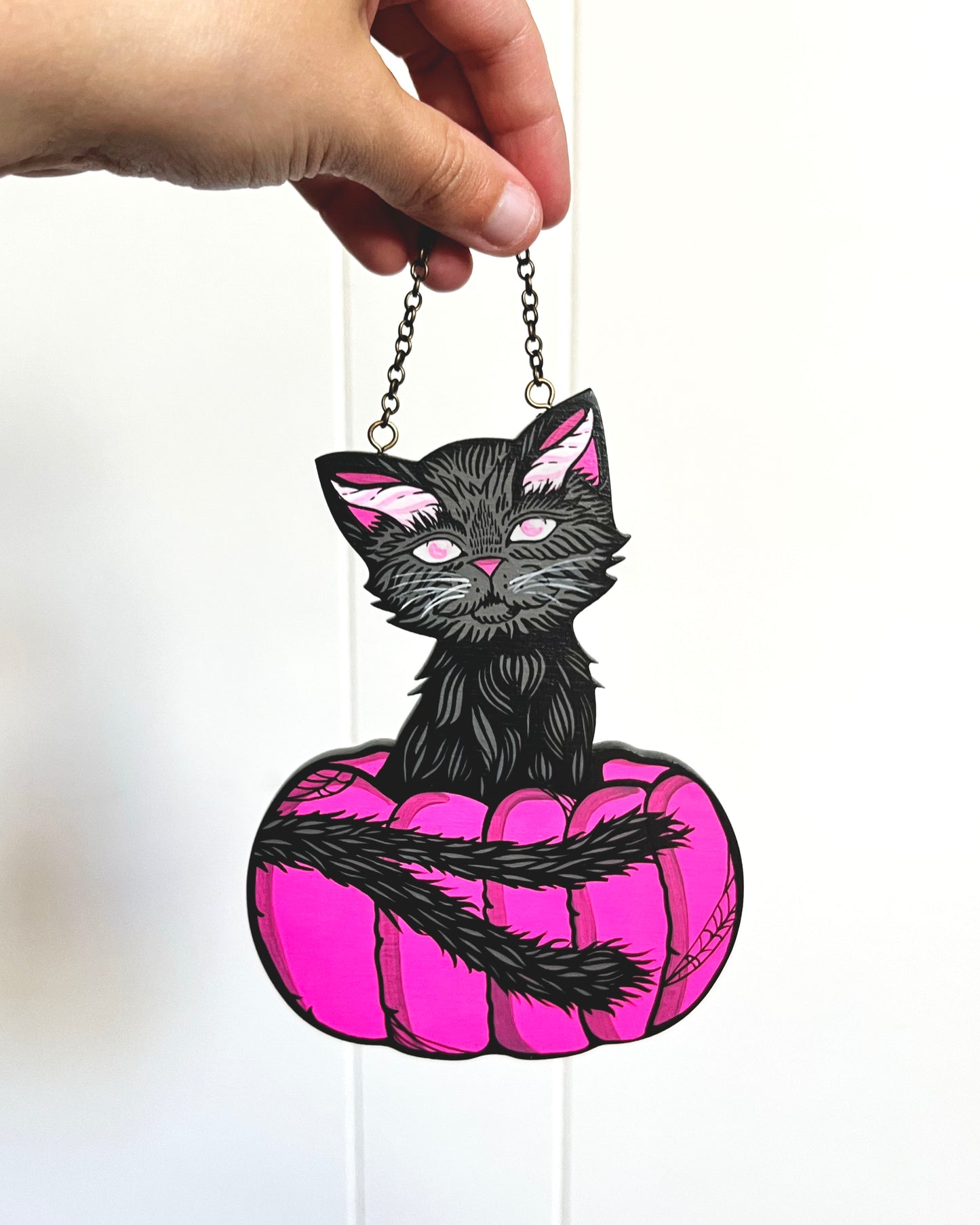 hand painted cat with horns and a double tail sitting in a pink pumpkin