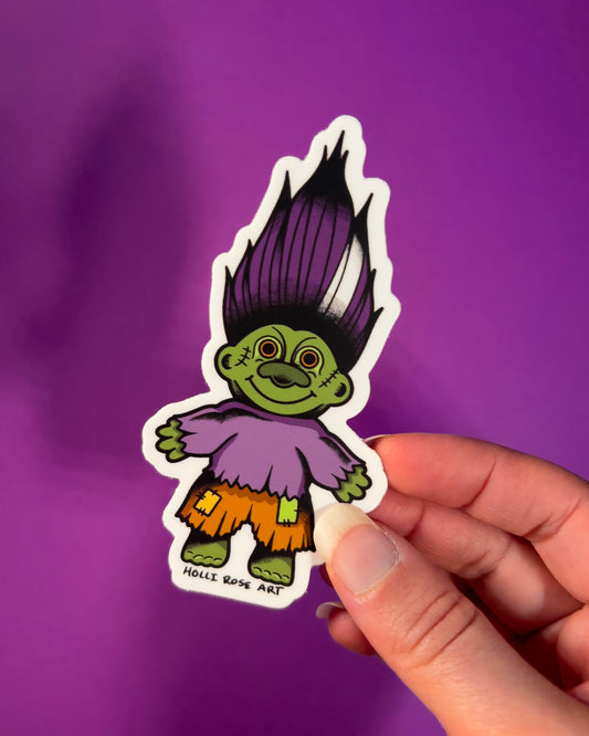 green troll sticker with purple hair and orange shorts