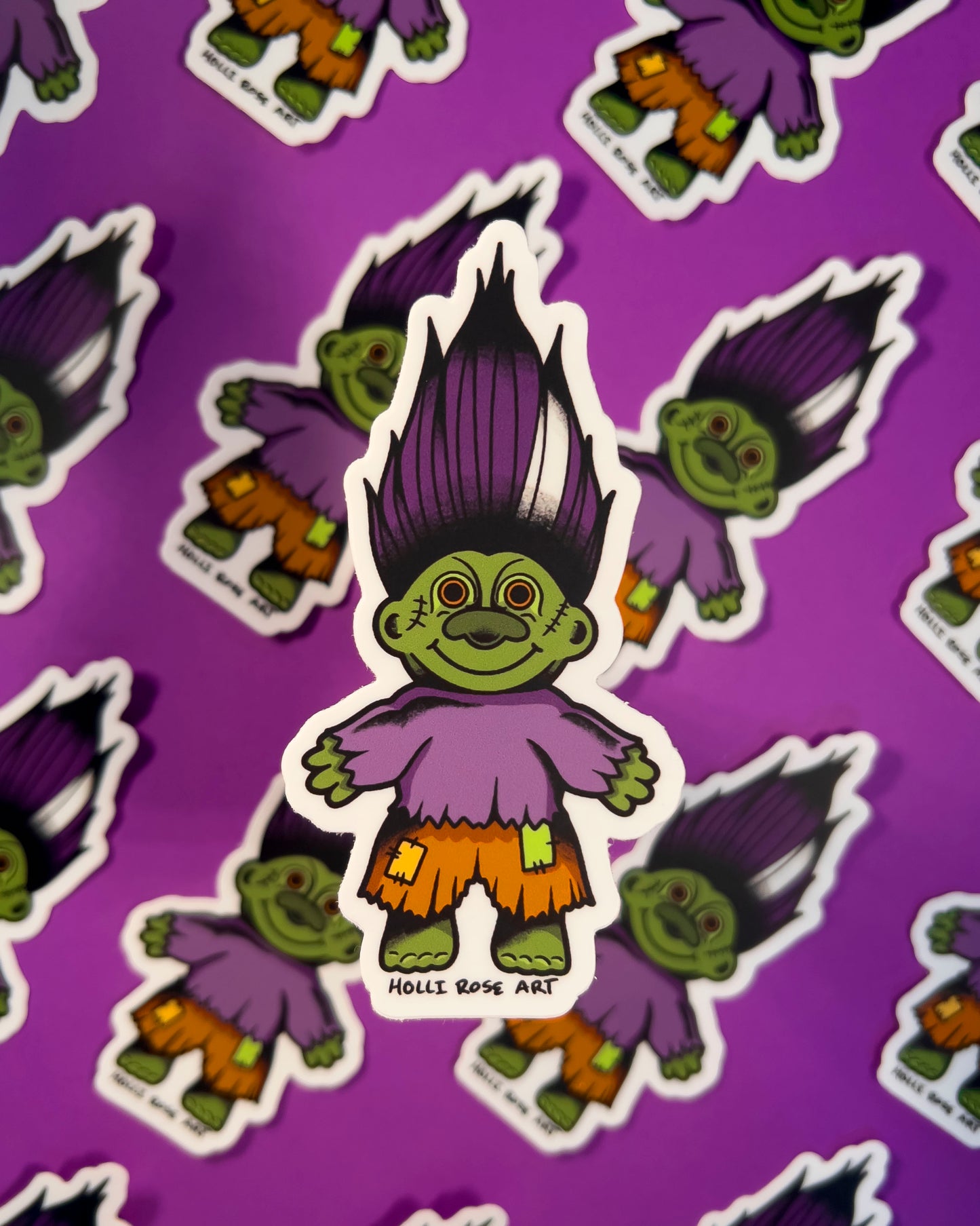 green troll sticker with purple hair and orange shorts
