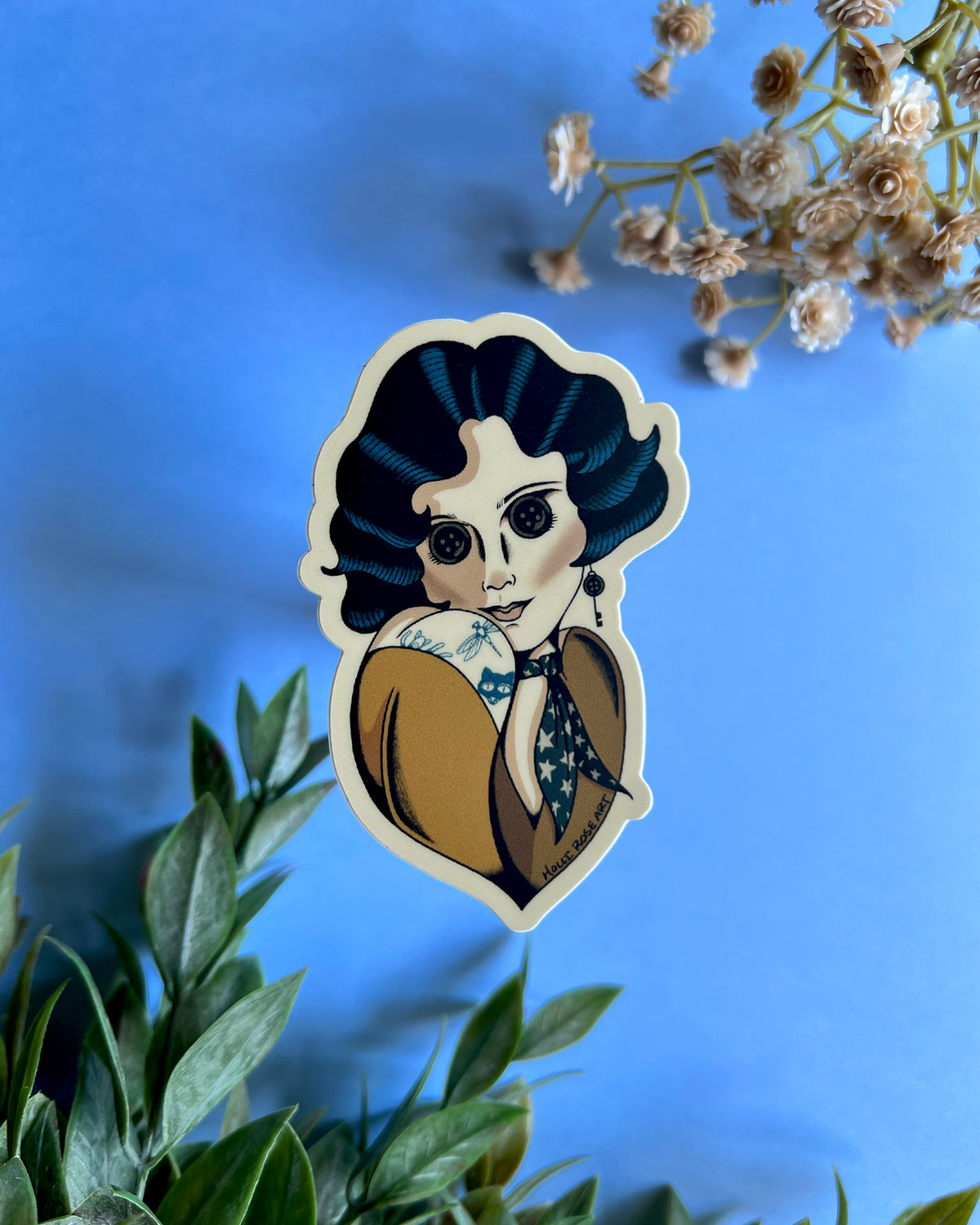 A sticker with a pinup style gal with blue hair, button eyes and a yellow shirt