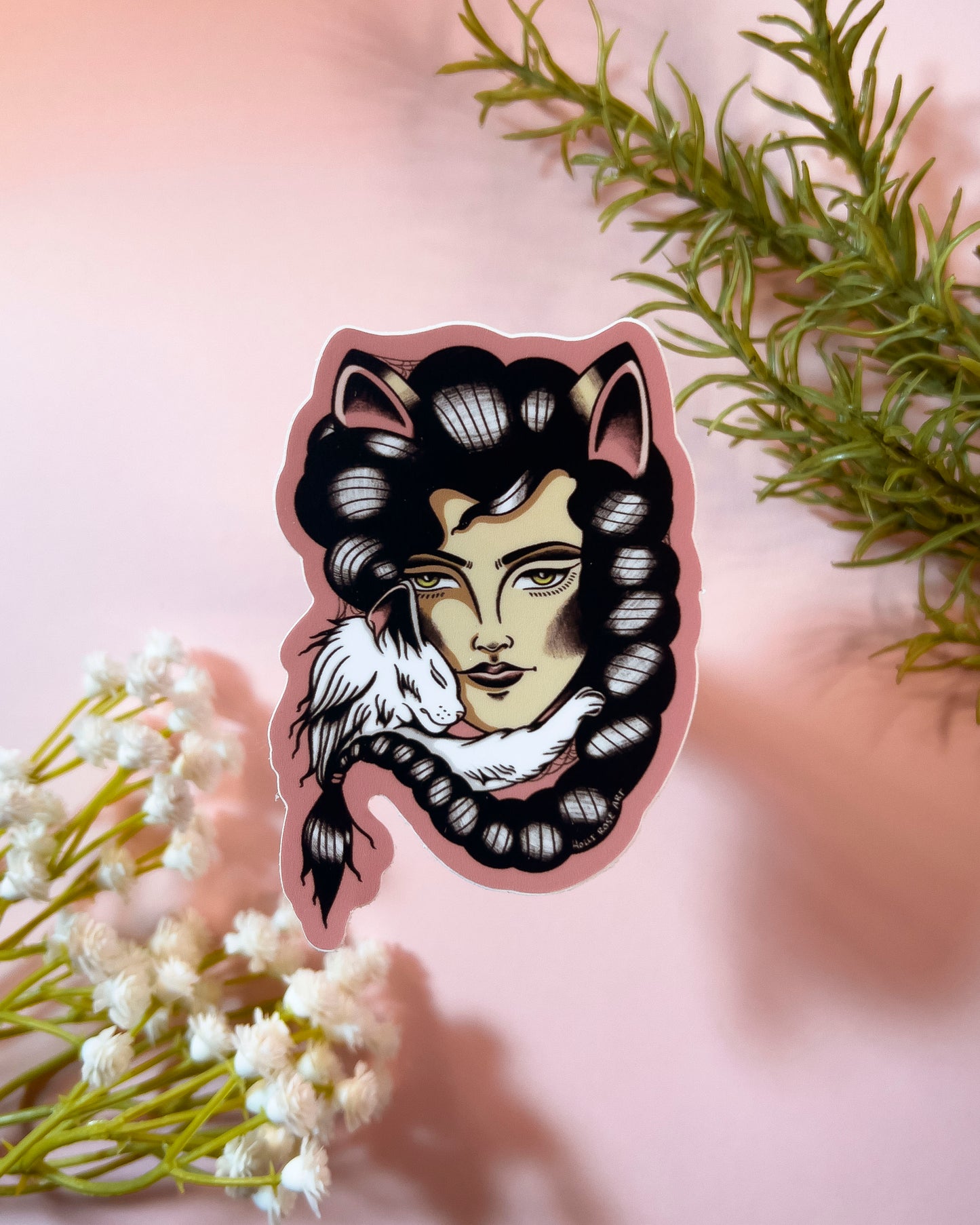 Sticker of a stylized face with animal ears and a feather on a pink background with greenery and flowers.