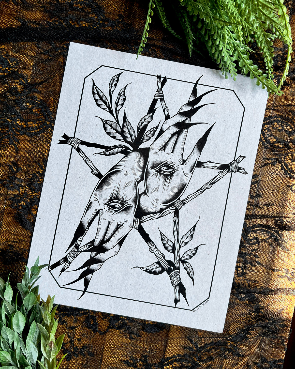 a print with Witchy hands with an eye in the center of the palm and sticks forming a witchy star around it and leaves