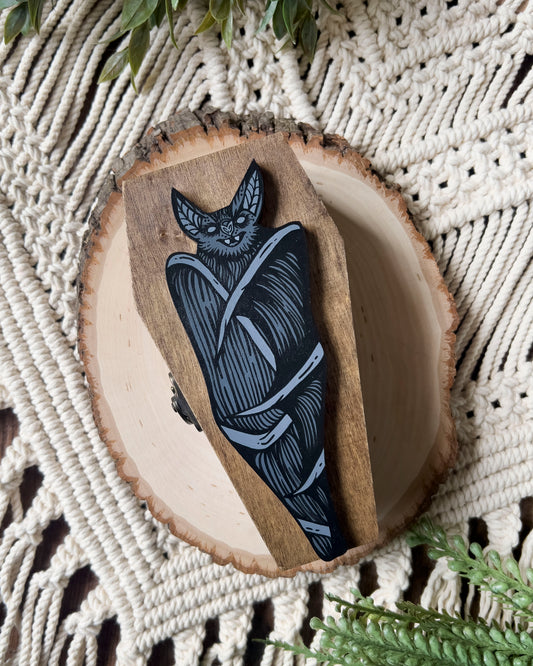 a coffin shaped trinket dish with a hand painted bat on it 
