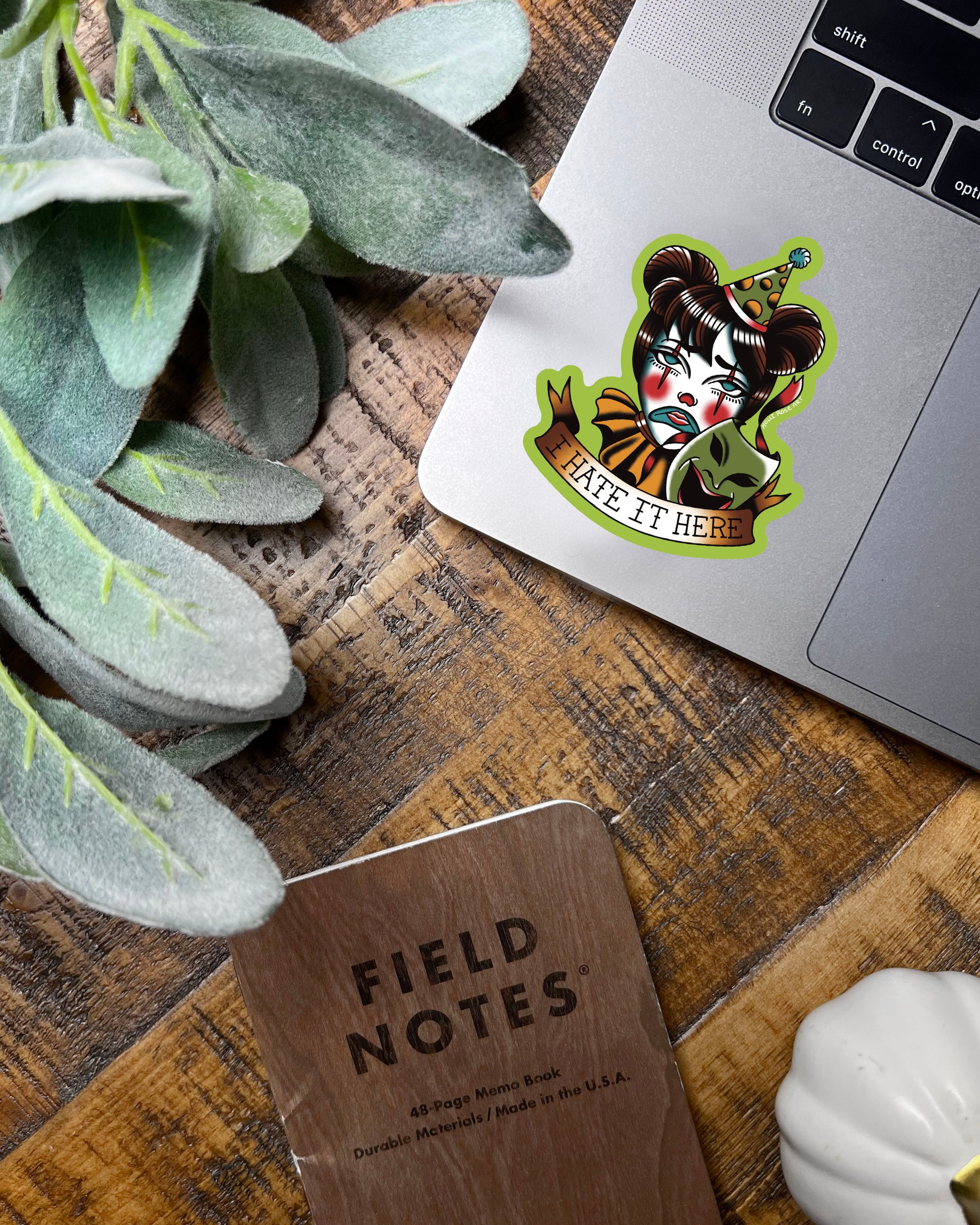 Sticker with a clown face and text 'I HATE IT HERE' on a laptop