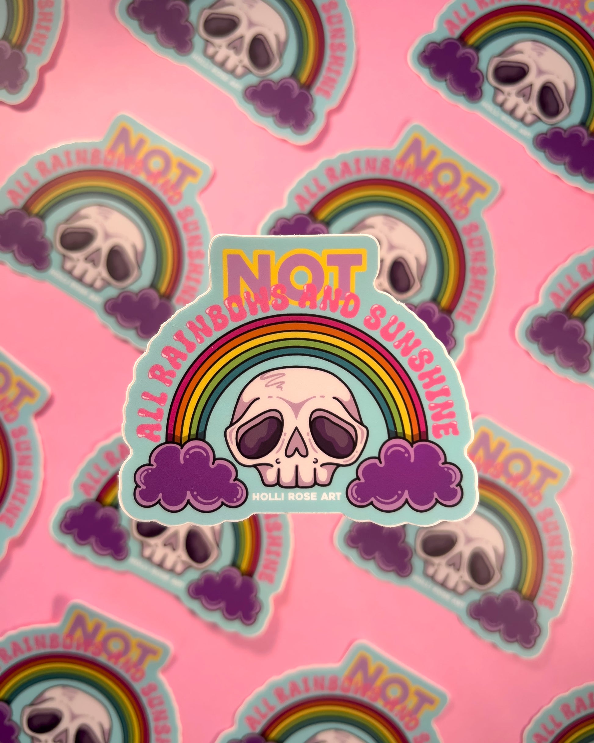 Stickers with skull design, rainbow, and 'Not All Rainbows Are Sunshine' text on a pink background.