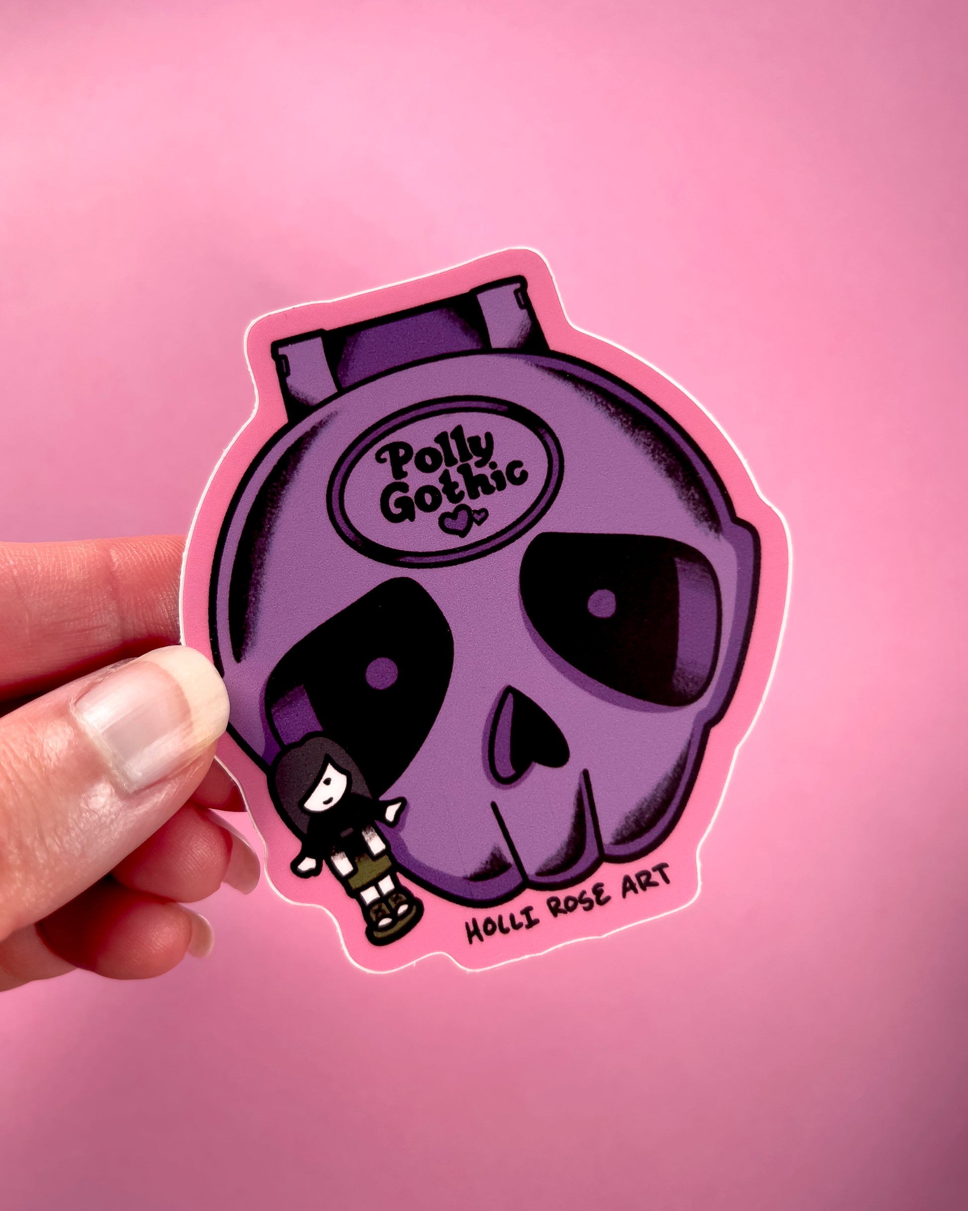 Purple skull sticker with 'Polly Gothic' text held against a pink background