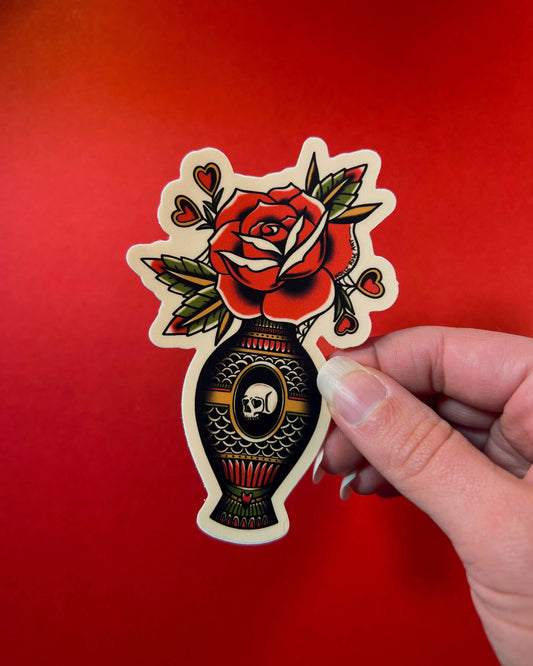 Sticker of a rose and vase design held against a red background