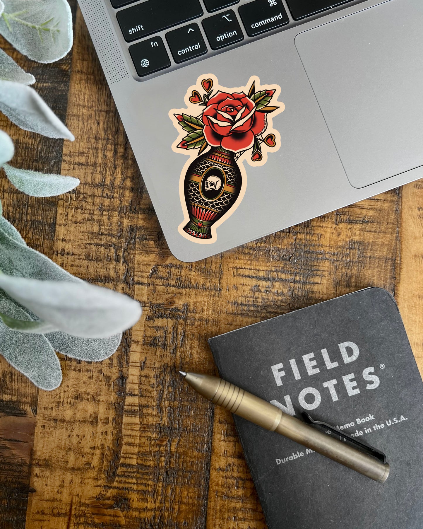A sticker with a rose and vase stuck to a laptop