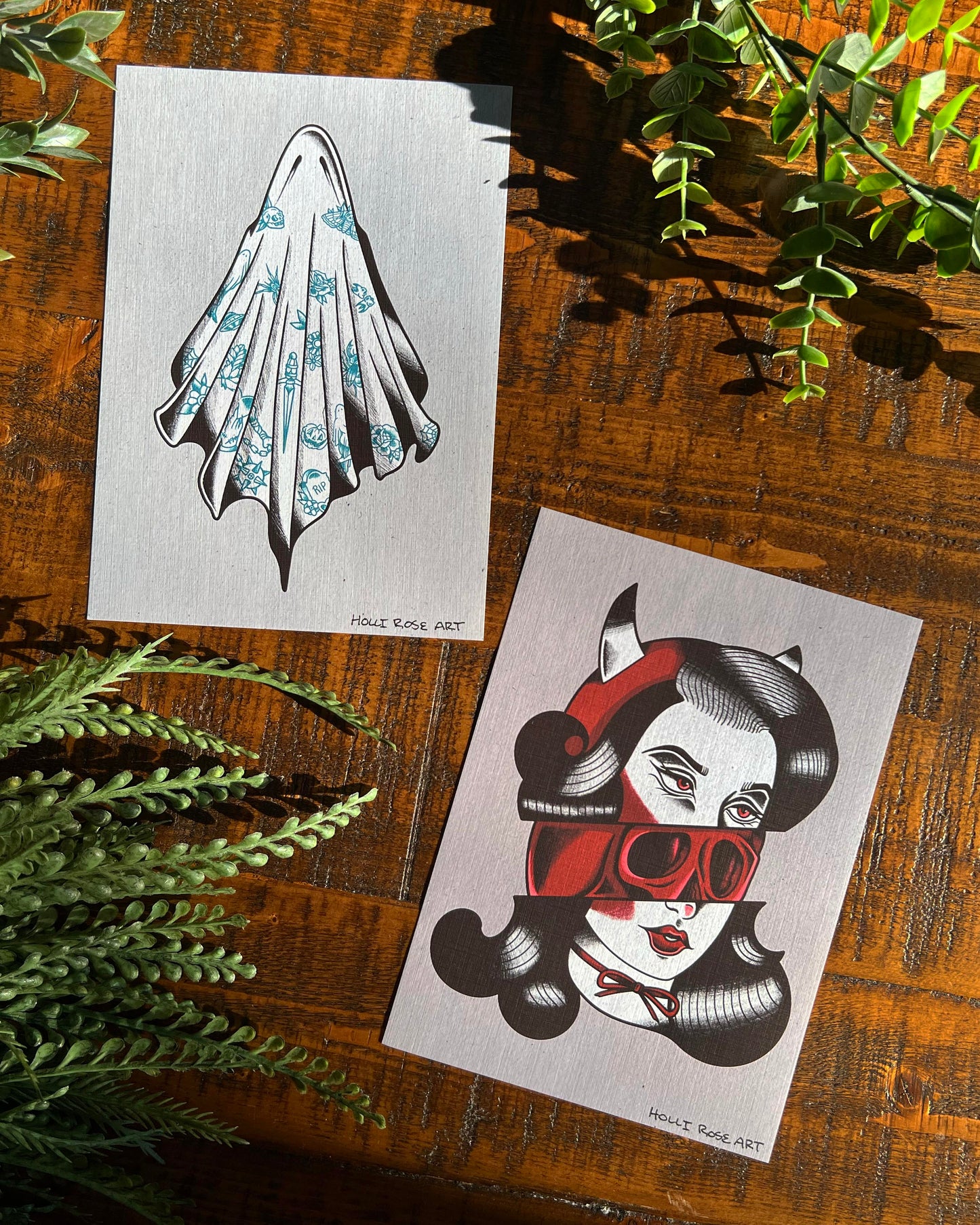 Art Print of a girl's face cut in half, showing a skull in the middle and another art print showing a ghost with tattoos