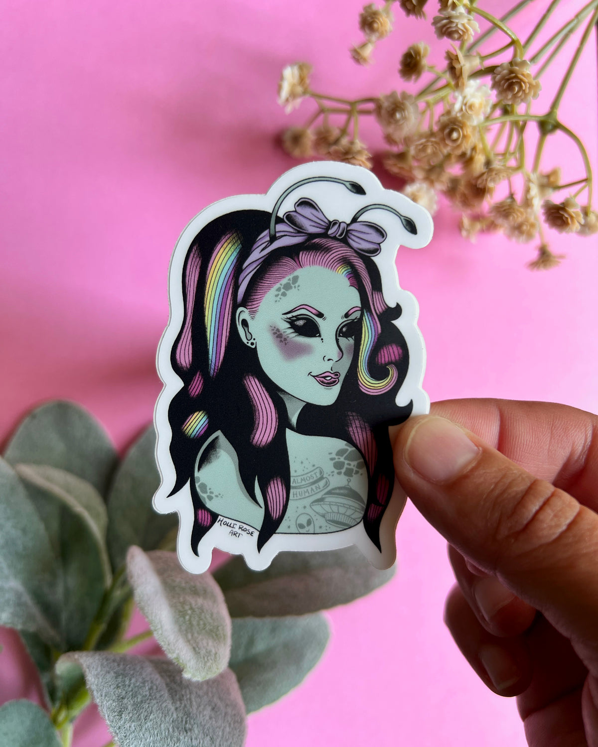 a sticker of an alien girl with rainbow and pink hair and space tattoos