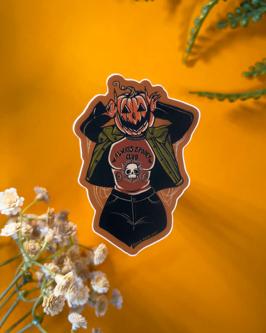 a pumpkin girl using her hands to make devil horns by her head wearing a shirt that says always spooky club shirt 