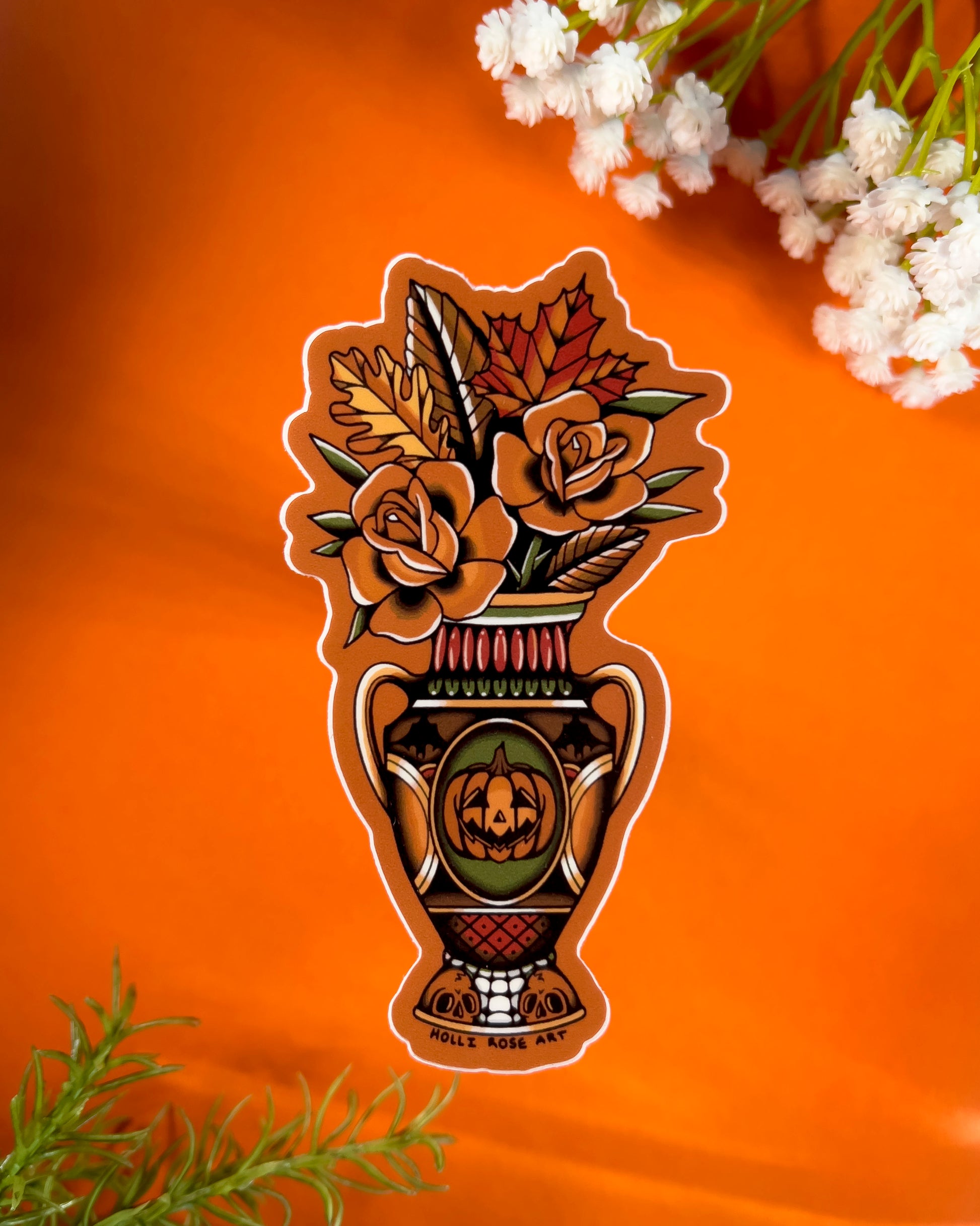 Decorative sticker with floral design and pumpkin face on an orange background