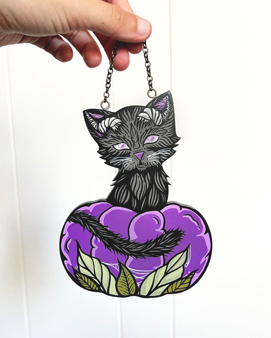 hand painted cat with horns and sitting in a purple pumpkin
