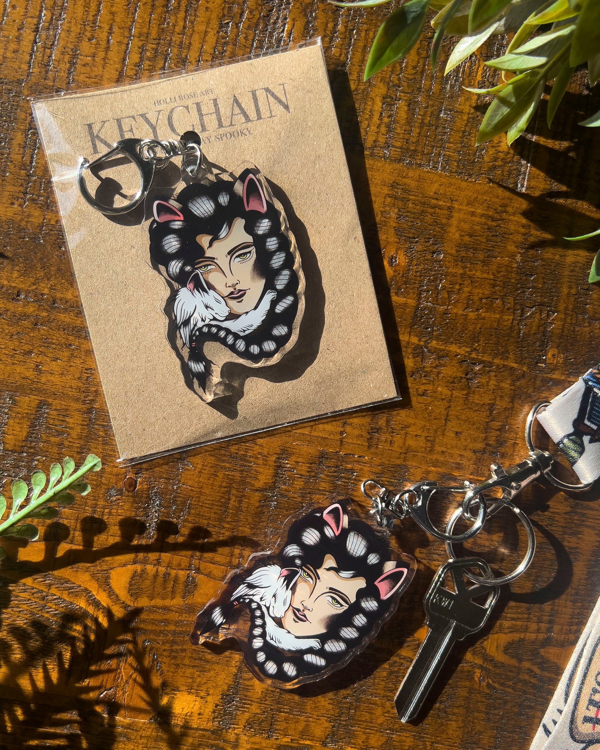 a keychain of a girl with cat ears and a white cat snuggling her face
