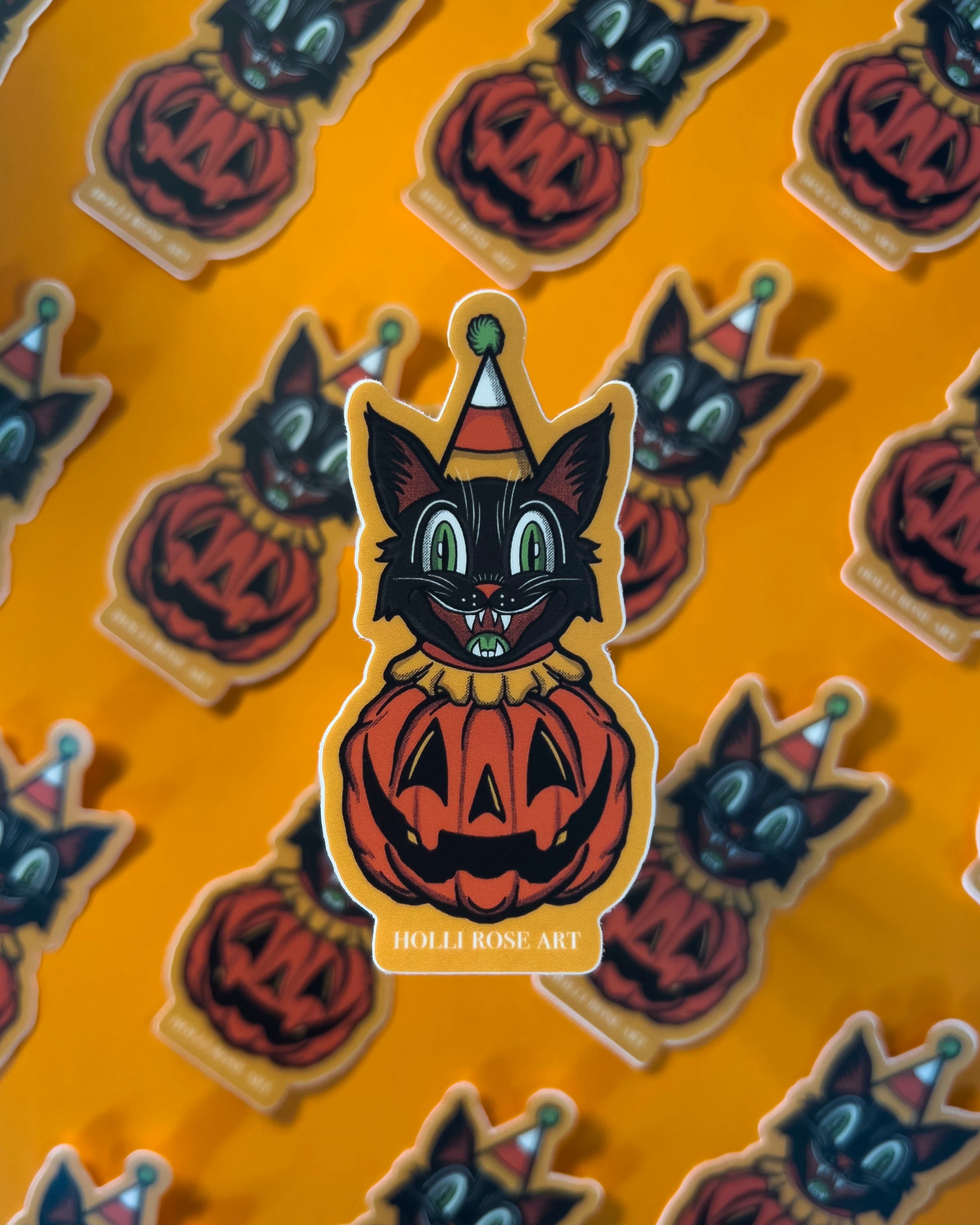 sticker of a clown cat popping out of a smiling pumpkin