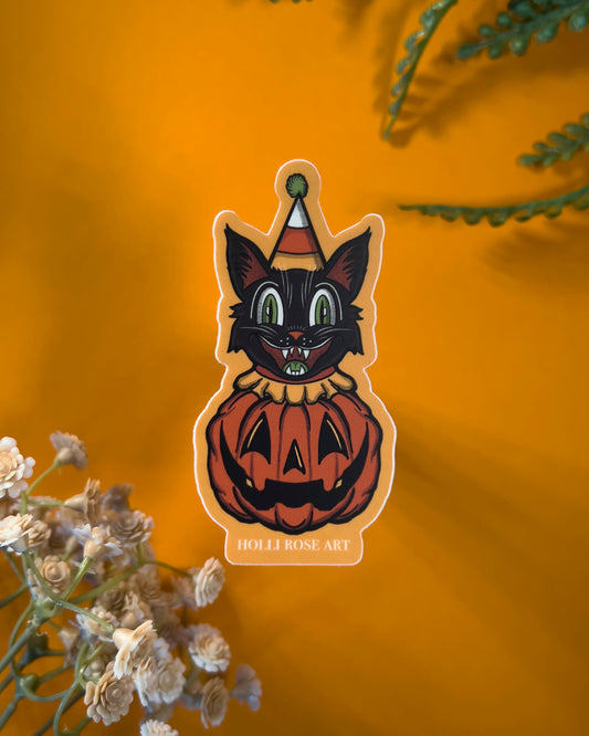 sticker of a clown cat popping out of a smiling pumpkin