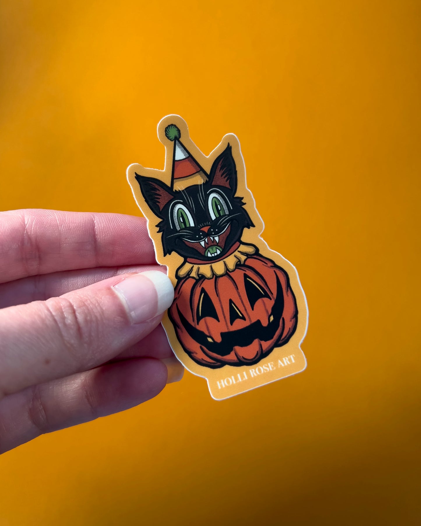 sticker of a clown cat popping out of a smiling pumpkin