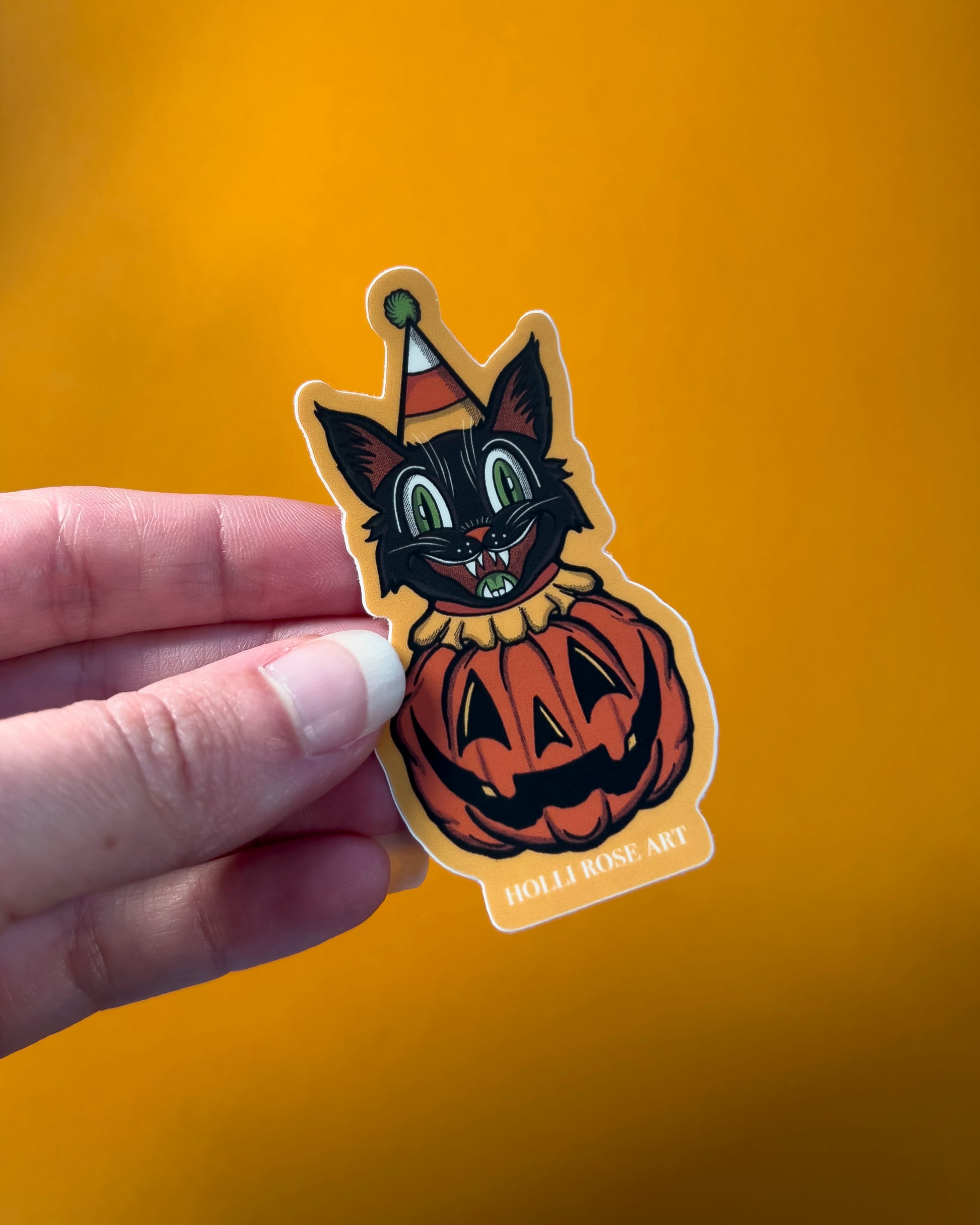 sticker of a clown cat popping out of a smiling pumpkin