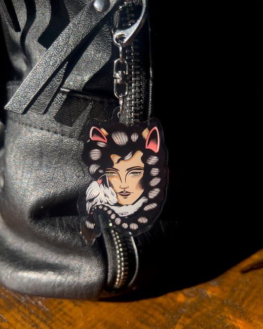 a keychain of a girl with cat ears and a white cat snuggling her face