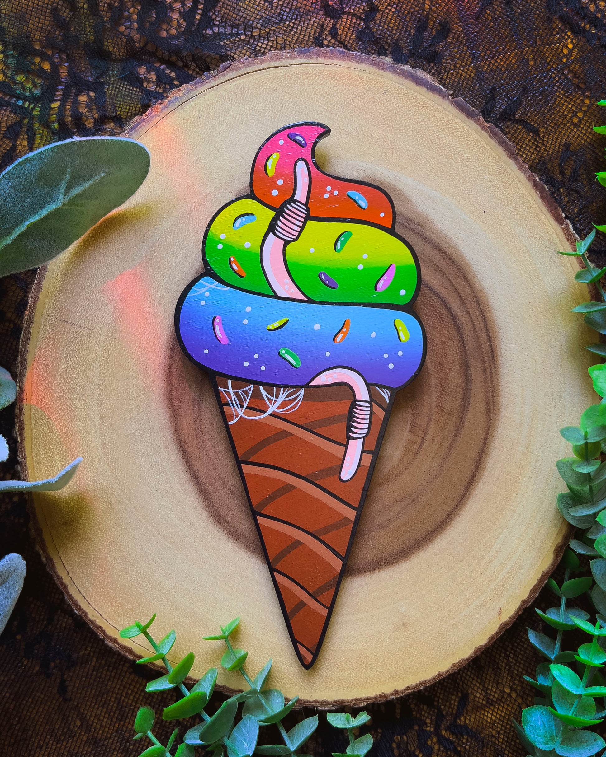 Colorful ice cream cone painting on a wooden background with greenery