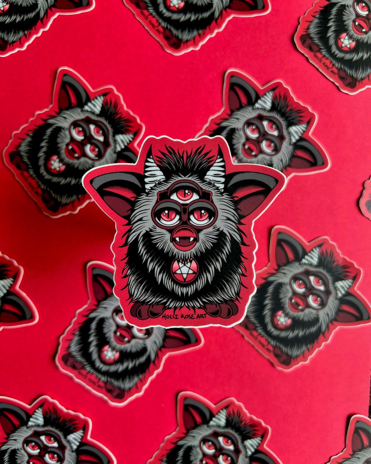 a sticker of a red and grey evil furb with 3 eyes and a satanic star