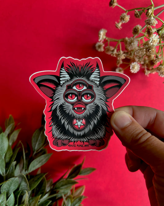 a sticker of a red and grey evil furb with 3 eyes and a satanic star