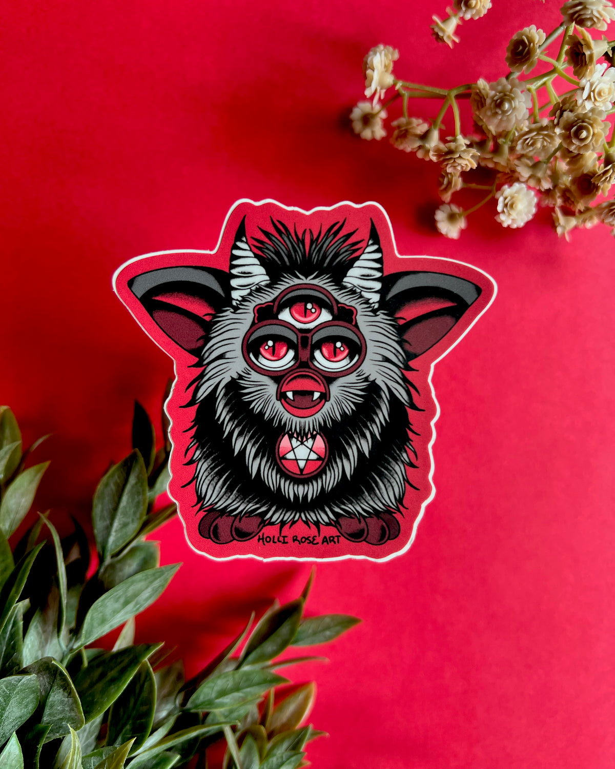 a sticker of a red and grey evil furb with 3 eyes and a satanic star