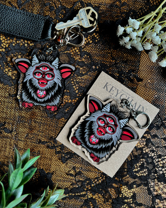 a three eyed evil furb keychain in black and red 
