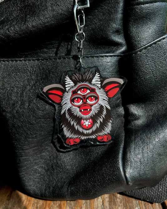 a three eyed evil furb keychain in black and red 