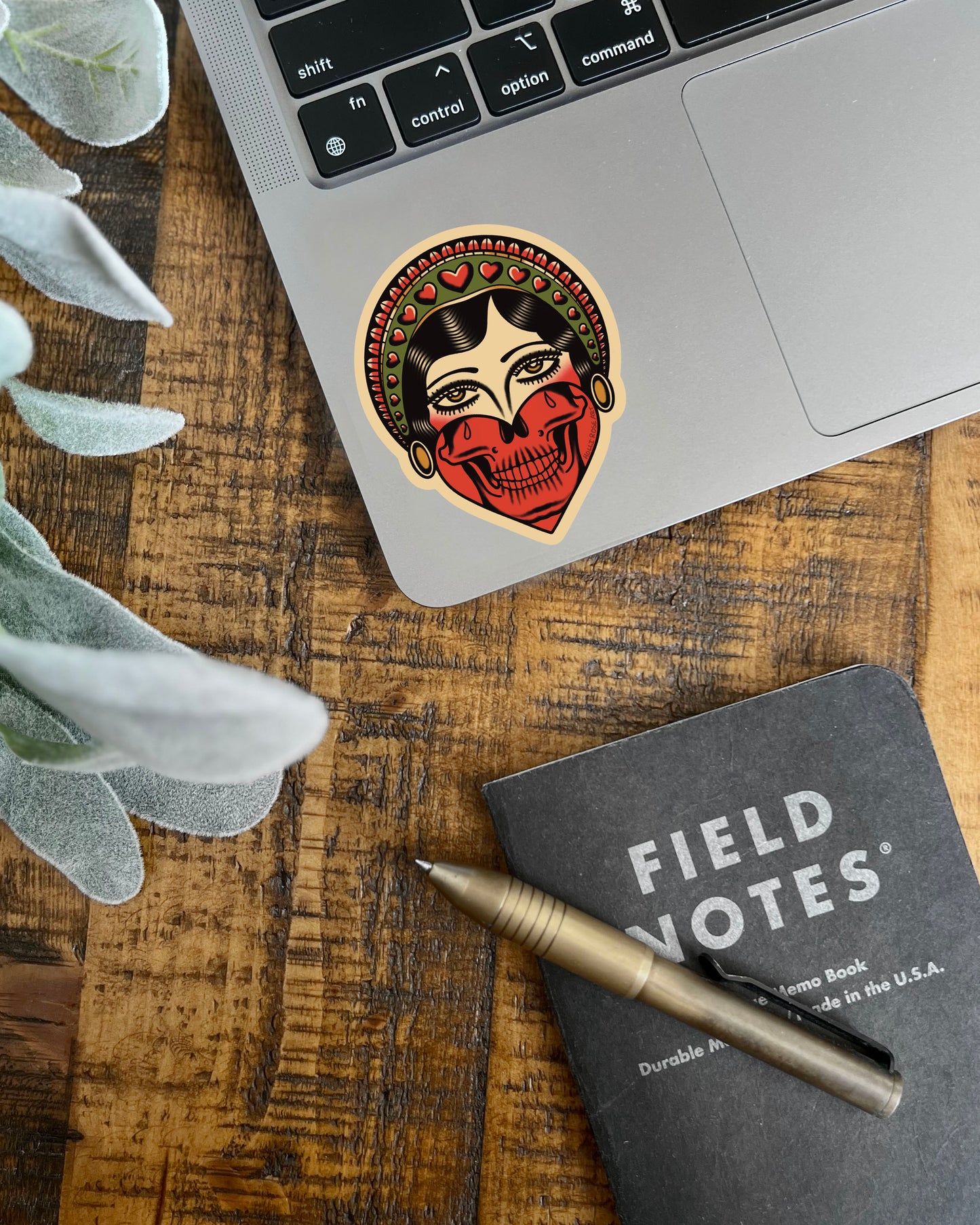 Sticker of a stylized face with skull design on a computer laptop