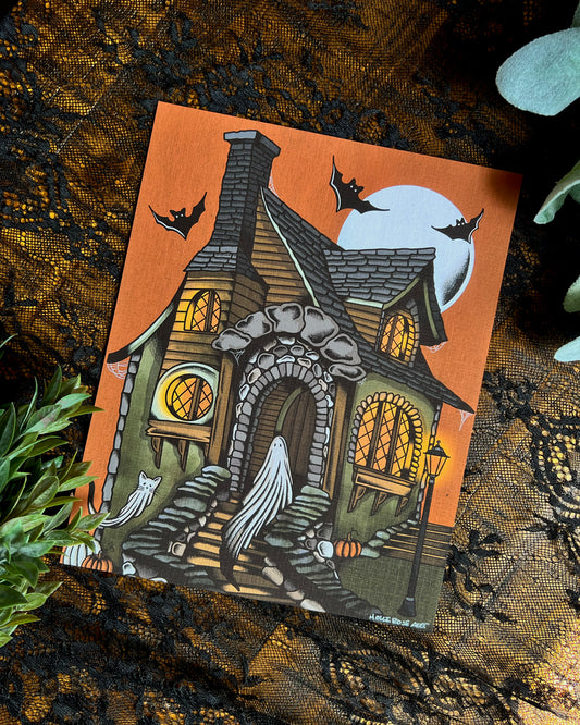 An art print with a ghost and a cat ghost in a cottage with an orange sky and a moon and bats.