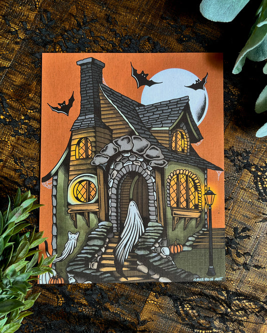 An art print with a ghost and a cat ghost in a cottage with an orange sky and a moon and bats.