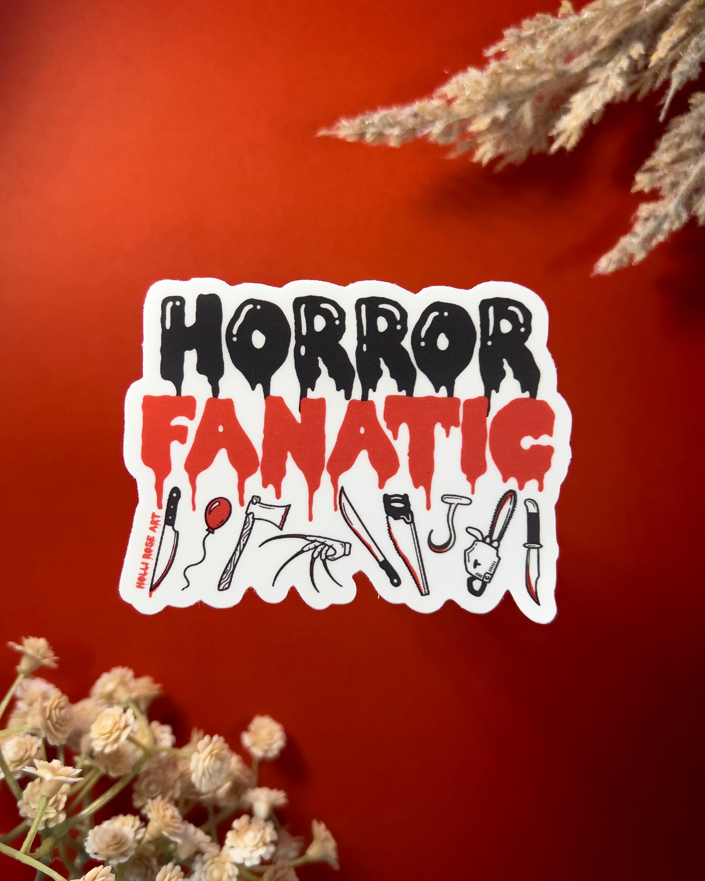 a sticker that says "horror fanatic" with various weapons on the bottom