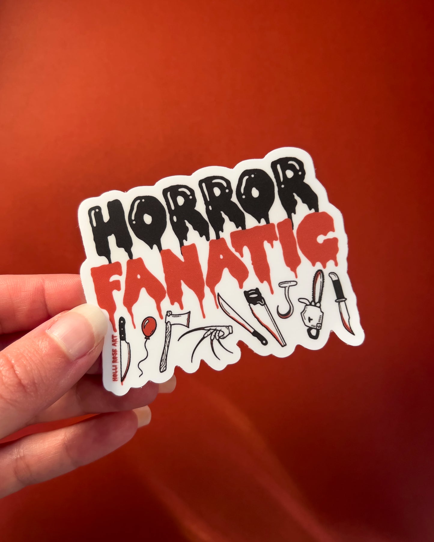 a sticker that says "horror fanatic" with various weapons on the bottom