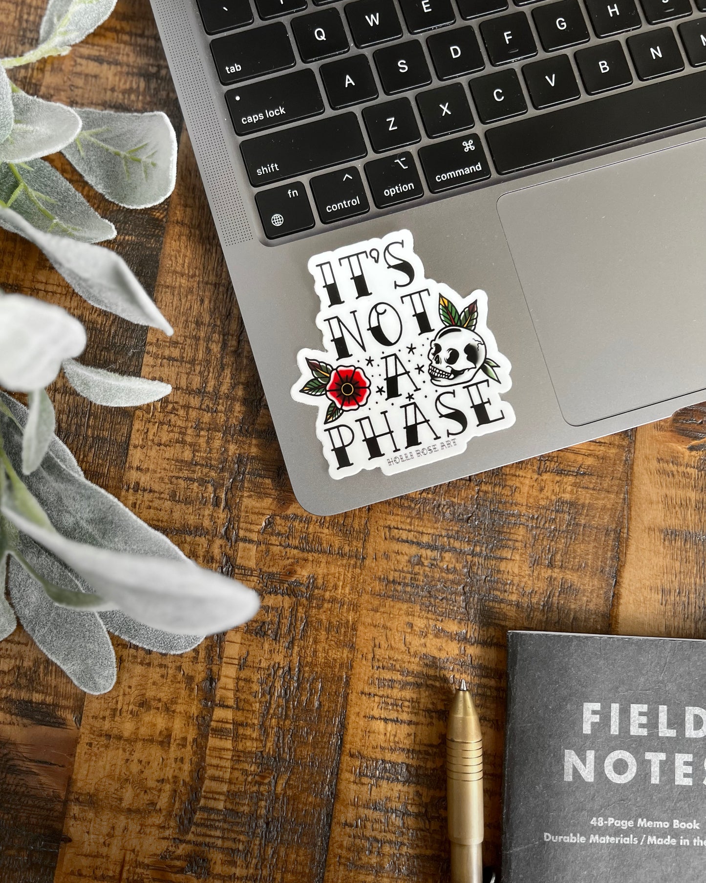 a sticker with a flower and a skull that says "its not a phase"