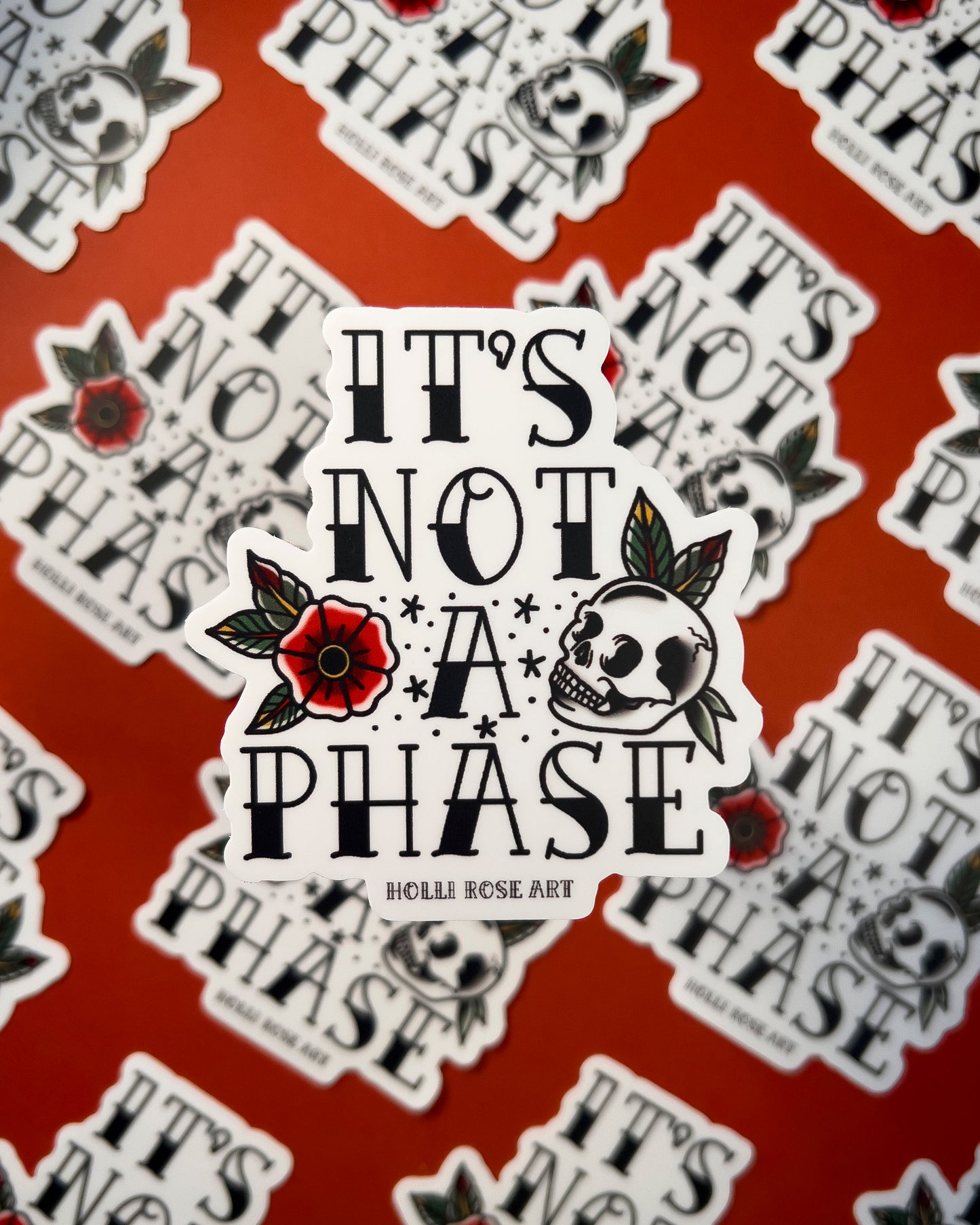 a sticker with a flower and a skull that says "its not a phase"
