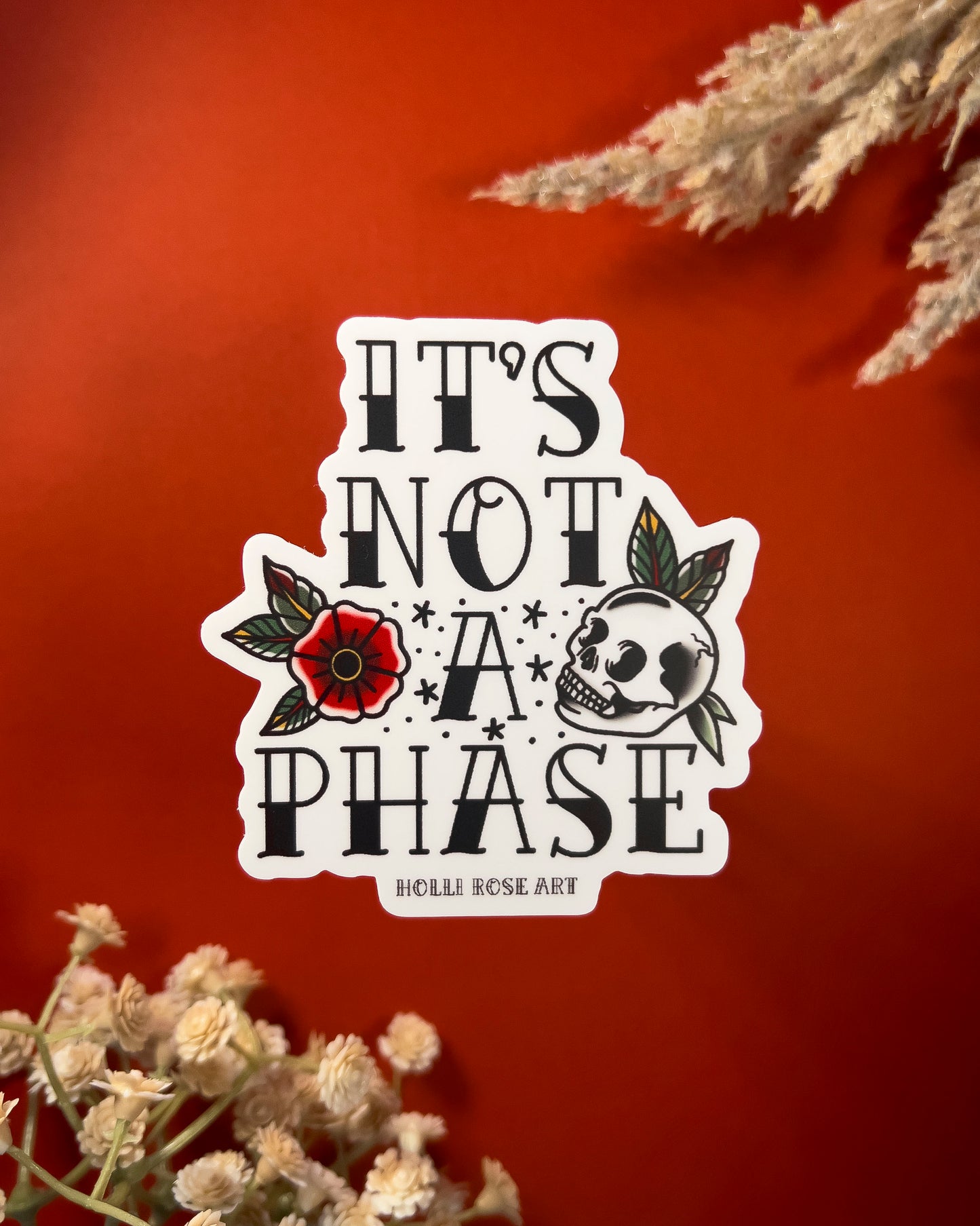 a sticker with a flower and a skull that says "its not a phase"