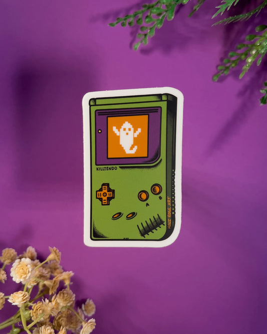 Sticker of a green hand gaming system with a ghost on the screen on a purple background
