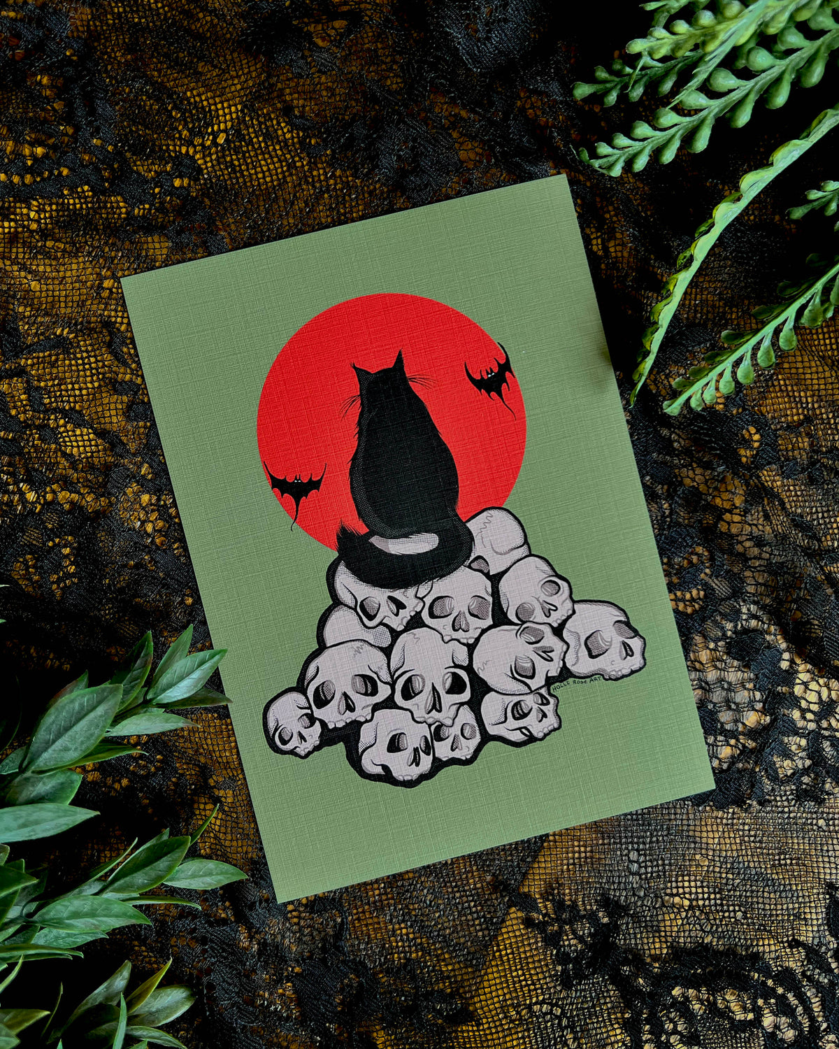 art print with a black cat  sitting on a pile of skulls
