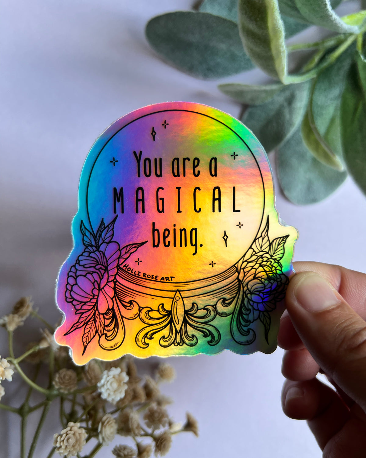 a colorful holographic sticker saying you are a magical being in a witch ball