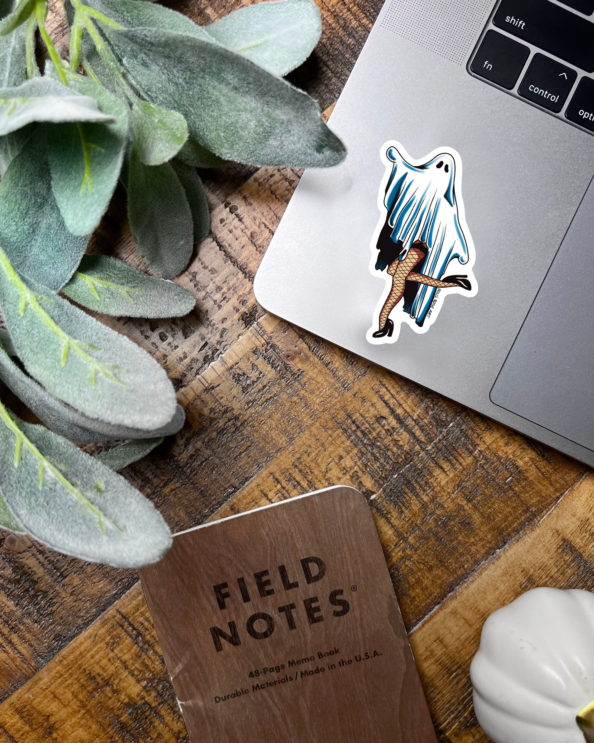 Sticker of a ghost in fishnet stockings on a teal background with flowers and leaves.